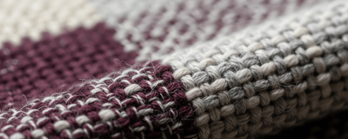 Gros plan sur la texture d'un tissu artisanal en fibres naturelles, tissé avec un motif géométrique bordeaux et écru.